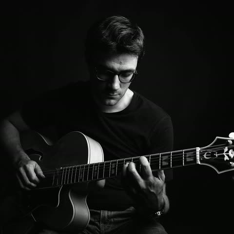 Löhstana David playing an acoustic guitar, head bowed — black-and-white portrait